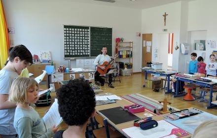 Bernhard Mikuskovics studiert Lieder mit den SchülerInnen der Volksschule Grosswarasdorf ein.